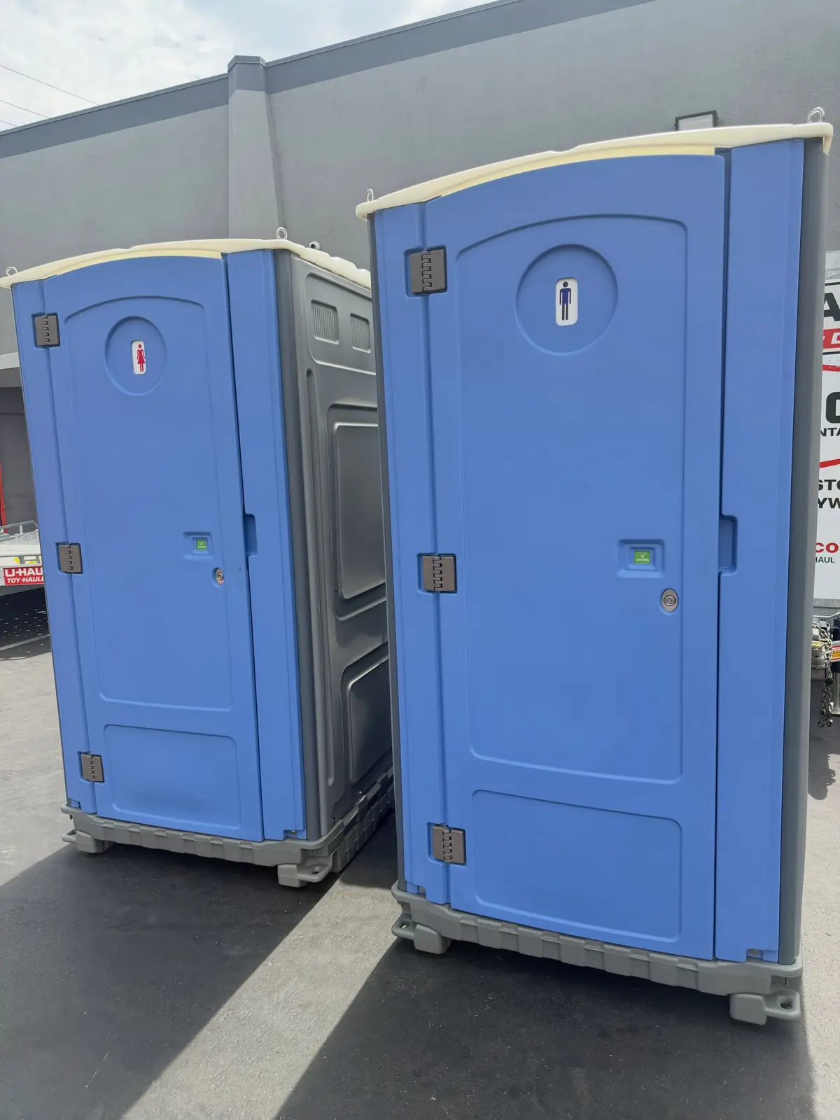 Two clean blue standard porta potties ready for delivery